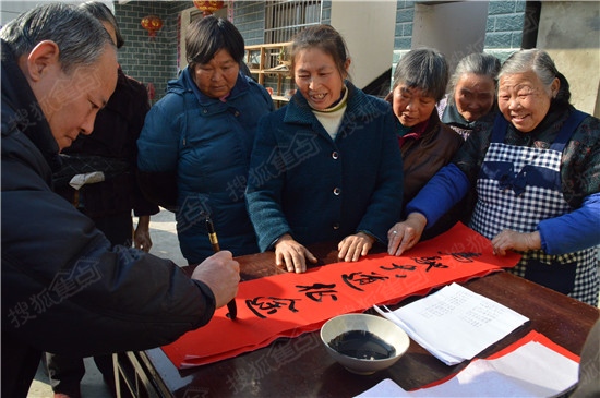 村委会广场前,纷纷领取红纸,由黄山市文联的书法家们为村民们现场写