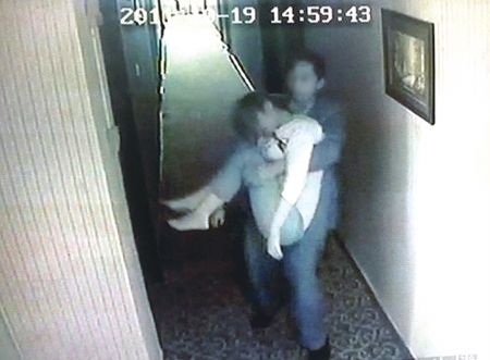 酒店监控录像显示：一名穿淡青色西服的男子抱着一名女子进入客房