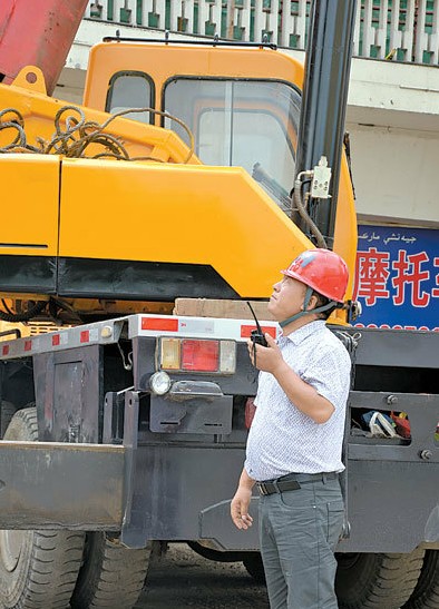 7月18日,夏明华正在指挥吊车工作.(记者 王媛媛摄)