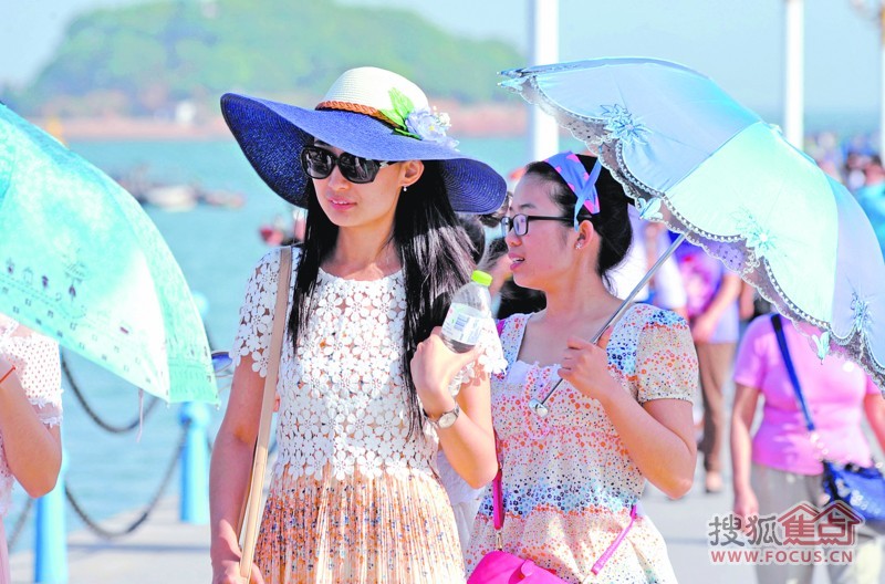 昨日,岛城烈日当空,游客戴着太阳帽,撑着遮阳伞在栈桥游玩.