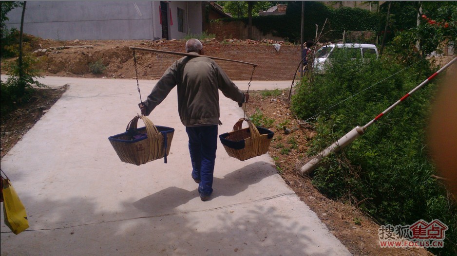 在村里的路上,我看到了一位七八十岁的老人,肩挑扁担,帮助家人