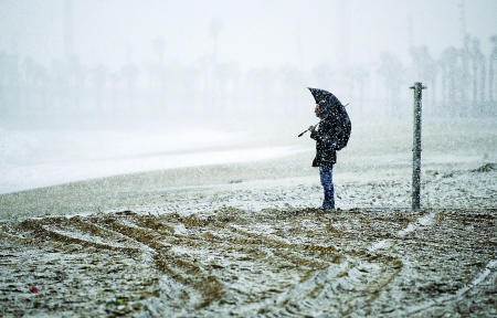 8日,西班牙巴塞罗那,人们撑伞在雪中行走