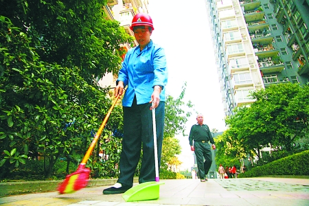 昨日,东海长洲小区,清洁工向兴美戴着安全帽在小区内打扫清洁